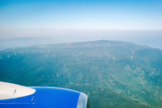 View of Wind Turbines From Airplane High Above Green Hills