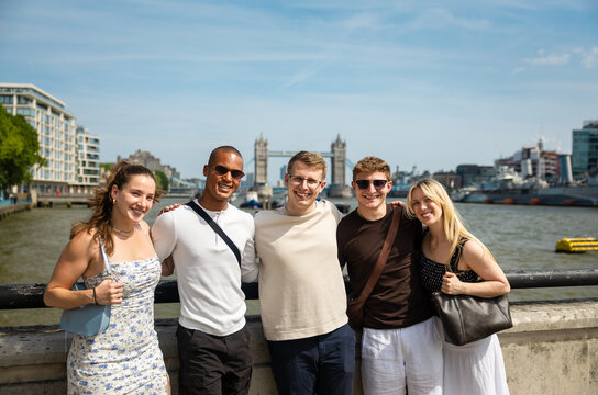Friends posing by the River Thames with Tower Bridge in London