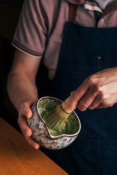 Close-up of barista whisking matcha tea in ceramic bowl