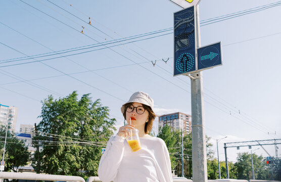Person Enjoys Drink While Standing Near Traffic Signals in City