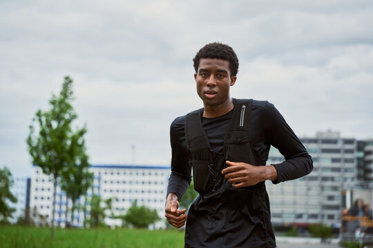 Young Man Runs in City Park During Cloudy Afternoon