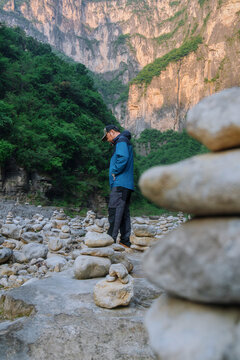 Lonely Hiker Contemplating in a Field of Stone Cairns at Sunset.