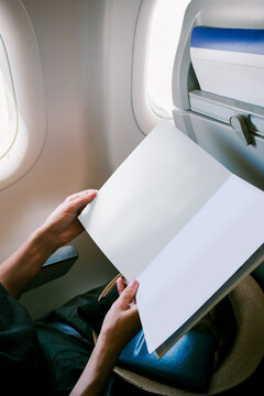 Female is holding a mockup magazine on the plane