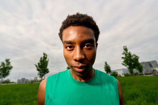 Young Athlete Poses in a Green Field Near a City on a Cloudy Day