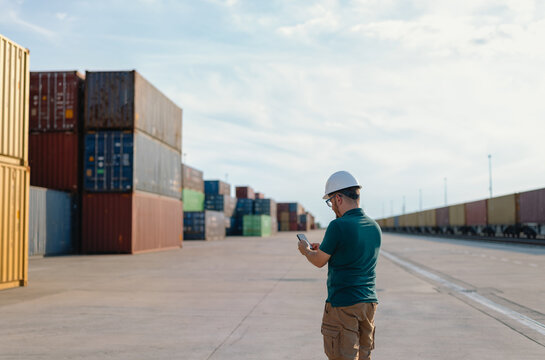 logistics supervisor in a hard hat inspecting a container yard 