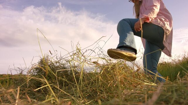 Female farmer standing on piles of grass hay in field