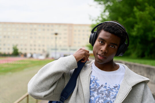 Young Man With Headphones Walks Outdoors in Urban Area