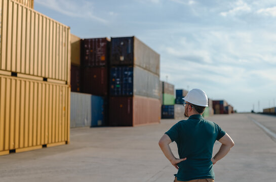 logistics supervisor in a hard hat inspecting a container yard 