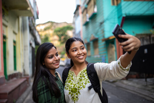 Two young girl taking selfie shots in the street of a city 