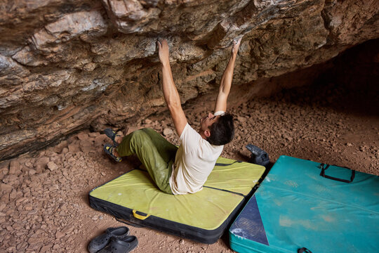 Climber practices bouldering in cave during daylight