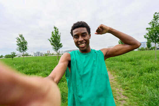 Young Man Smiles and Poses for a selfie in Green Field During Daytime