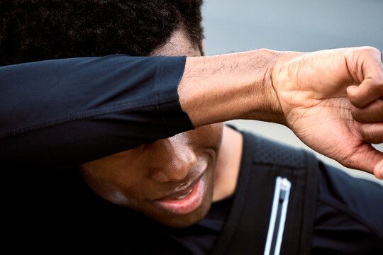 Man Wipes Sweat From Forehead After Exercise in Outdoor Area