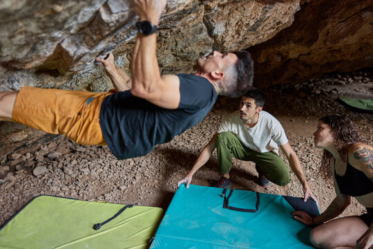 Climbers train in cave with mats for safety in bright daylight