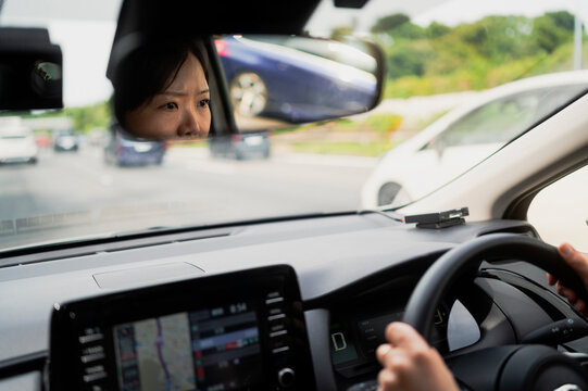 Woman Driving Car Viewed Through Rearview Mirror