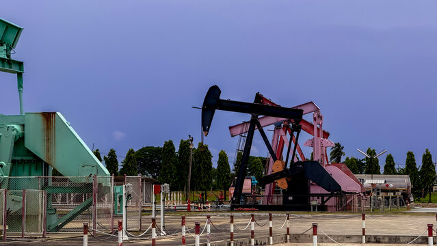 Oil and gas production concept. Pumpjack extracting crude oil at an onshore petroleum field during sunset. Energy, oilfield, drilling, petroleum, industry