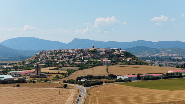 Berdun village on a hilltop with traditional houses and a church dome dominating the landscape, surrounded by cultivated fields and mountains