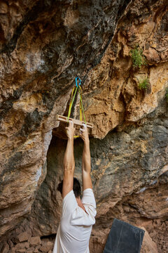 Climber practices grip strength on rock wall in outdoor location