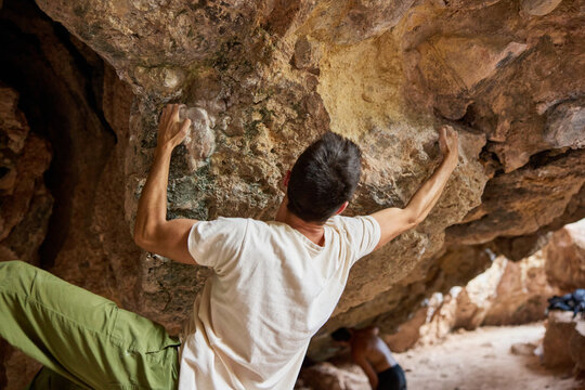 Climber works on bouldering problem at rocky location in dayligh