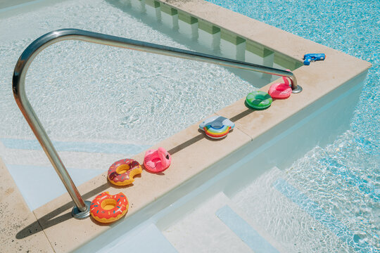 Colorful inflatable pool floats arranged beside swimming pool