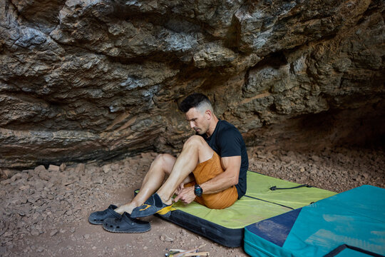 Climber prepares gear inside cave for rock climbing adventure