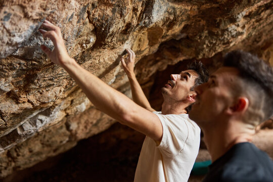 Climbers focus on rock wall while preparing for their next move