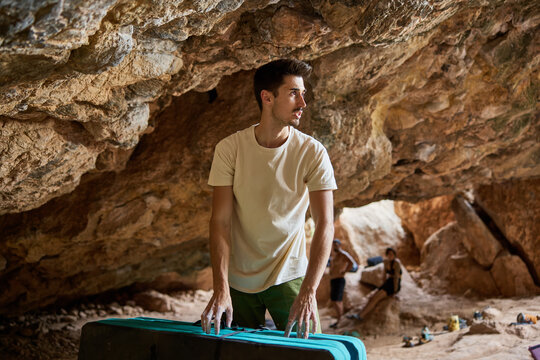 Man climbs rocks in cave with climbing gear during daylight hour
