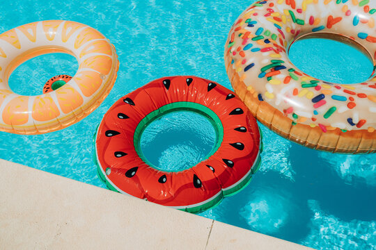 Colorful inflatable pool rings floating in bright blue swimming 