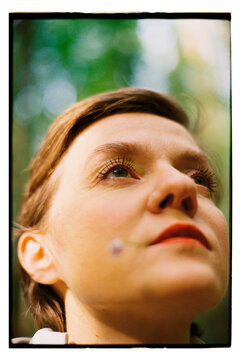Girl looking up in a forest setting with a thoughtful expression