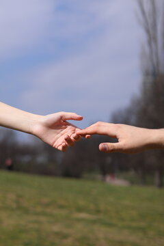 Man and woman barely touching fingers outdoors, concept of separation, distance, love, or support with copy space