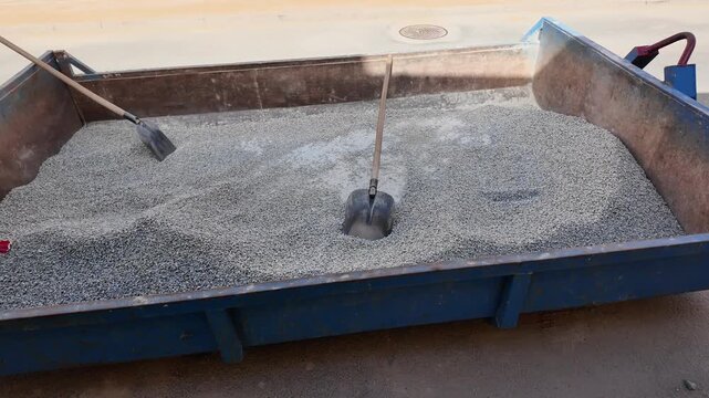Construction site skip filled with gravel and shovels ready for work