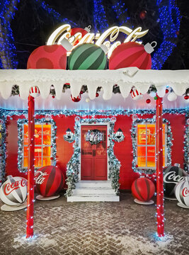 Chisinau, Moldova - January 10, 2026: A festive Coca-Cola themed house brightly decorated for Christmas with giant baubles, snowy eaves, and glowing lights. Magical winter holiday night background