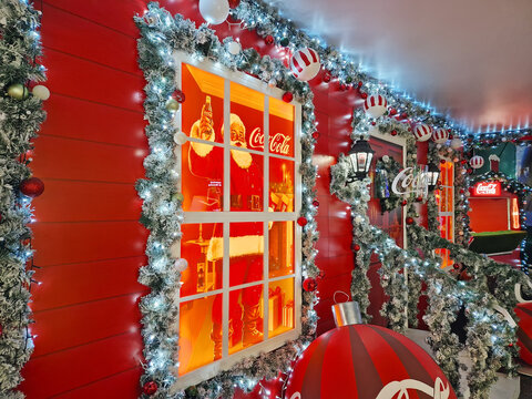 Chisinau, Moldova - January 10, 2026: a festive Coca-Cola booth facade decorated with frosted pine garlands and sparkling Christmas lights. Santa Claus holding a classic Coke bottle