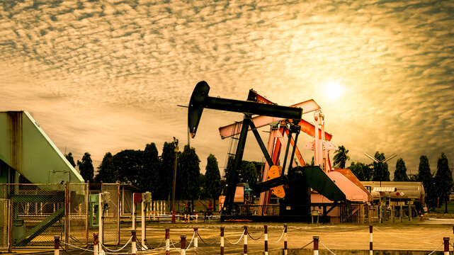 Oil and gas production concept. Pumpjack extracting crude oil at an onshore petroleum field during sunset. Energy, oilfield, drilling, petroleum, industry