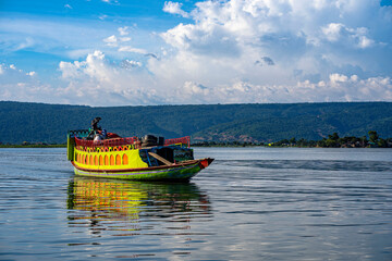 Fototapeta premium A scenic view of traditional and modern luxury houseboats carrying tourists across the vast freshwater wetland of Tanguar Haor in Sunamganj, Bangladesh, under a bright blue sky.