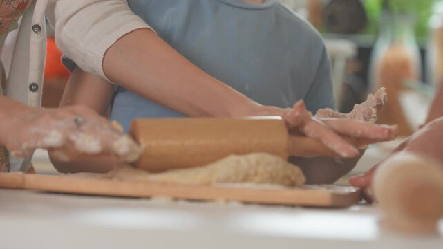 Family shaping and cutting dough on a floury worktop in a sunlit kitchen