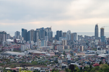 Fototapeta premium Panoramic urban skyline with coastal horizon seen from hilltop point.