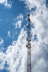 Obraz premium High Voltage Power Transmission Tower and Electrical Lines Against Blue Sky with Industrial Steel Pylon, Energy Infrastructure and Communication Technology Background