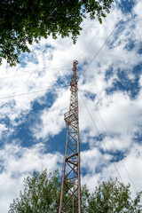 Obraz premium High Voltage Power Transmission Tower and Electrical Lines Against Blue Sky, Industrial Metal Structure for Energy Distribution and Modern Communication Infrastructure Technology