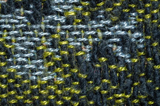 Macro close-up of black woven fabric with yellow and silver thread details, suitable for textile, craft, pattern, background, and material design themes.