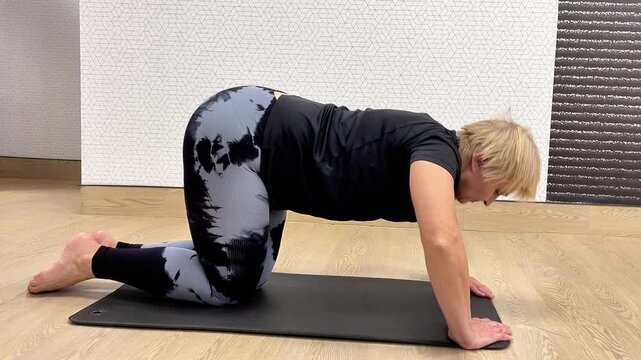 A person performs a stretching exercise on a mat at an indoor gym. The focus is on flexibility and proper form.