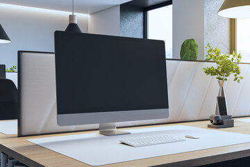 Fototapeta premium Blank black computer monitor mockup on wooden desk with white keyboard and green plant in modern office interior with panoramic windows. 3D Rendering
