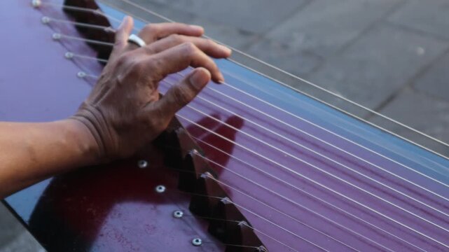 Someone is playing the kecapi, a Sundanese musical instrument.