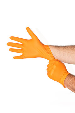 Hands putting on or donning bright orange, textured nitrile gloves in front of white background
