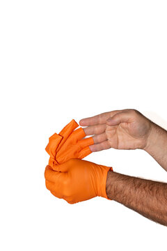 Hands taking off bright orange, textured nitrile gloves in front of white background