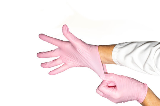 Hands putting on or donning pink nitrile gloves in front of white background