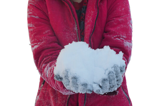 A girl holding snow in her hands on a white background. The girl is wearing a pink jacket.