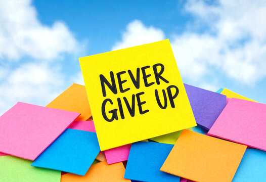 Bright colorful sticky notes with never give up message for motivation and inspiration under blue sky