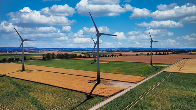 Windkraftanlagen &uuml;ber deutschen Feldern unter blauem Himmel