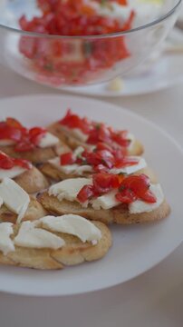 Spoon adds chopped tomato and herbs over mozzarella on toasted bread