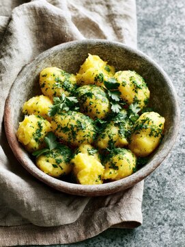 Freshly cooked potatoes garnished with herbs in rustic bowl